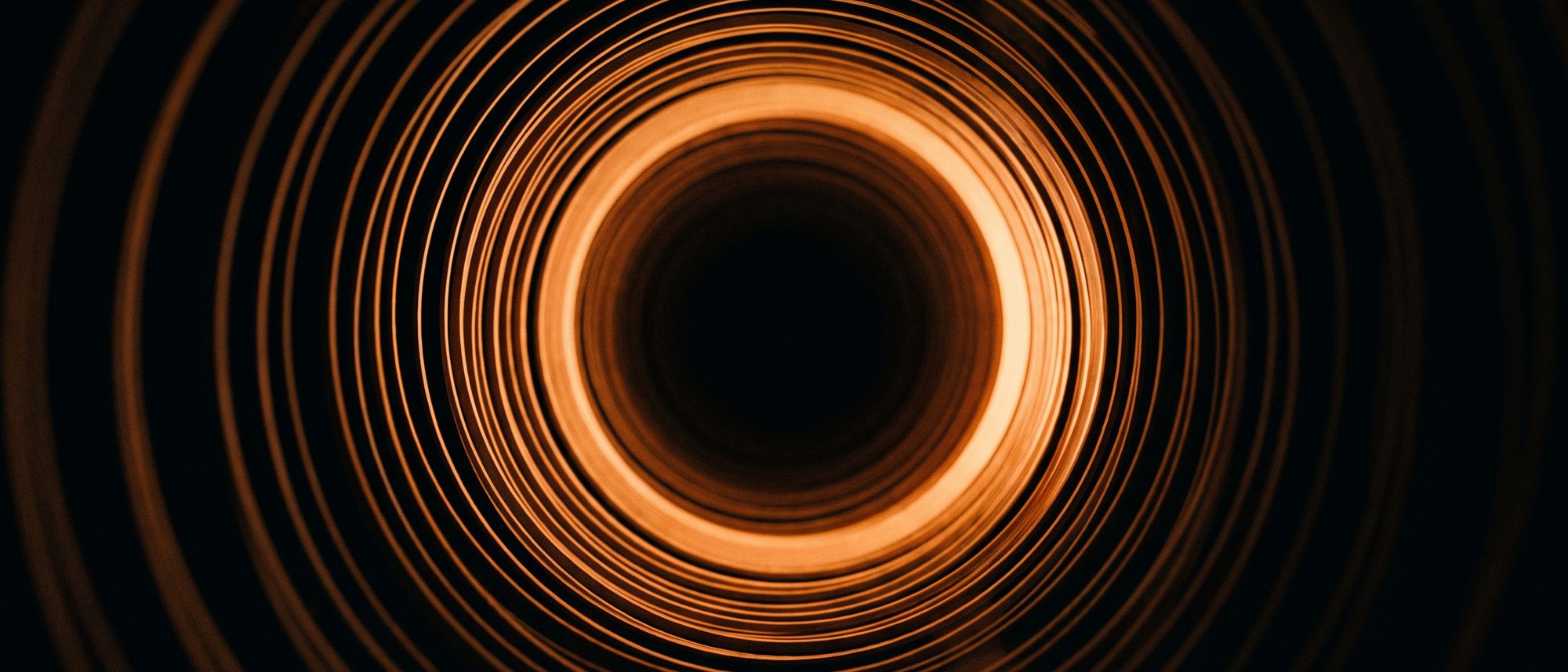 Abstract orange and black composition of concentric rings with a single ring brightly lit